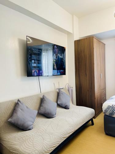 a living room with a couch with a tv on the wall at City View Studio Unit at Centrio Tower beside Ayala Mall in Cagayan de Oro
