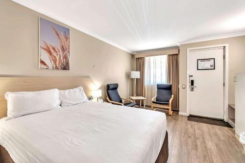 ein Hotelzimmer mit einem Bett und zwei Stühlen in der Unterkunft Quality Inn Railway Motel in Kalgoorlie