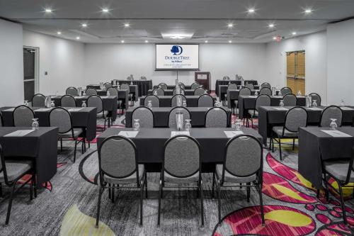 a conference room with tables and chairs and a screen at DoubleTree by Hilton Sarasota Bradenton Airport in Sarasota
