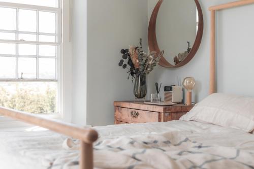 a bedroom with a bed and a mirror at Boutique Beach Retreat in Westward Ho
