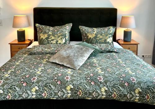 a bed with a green comforter and two lamps at Alte Schüre in Elpe