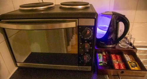 a microwave oven with a kettle on top of it at Cosy Studio in London
