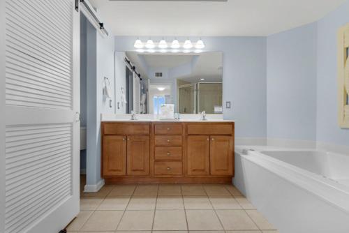 uma casa de banho com uma banheira e um espelho grande em St. Lucia 704 em Destin