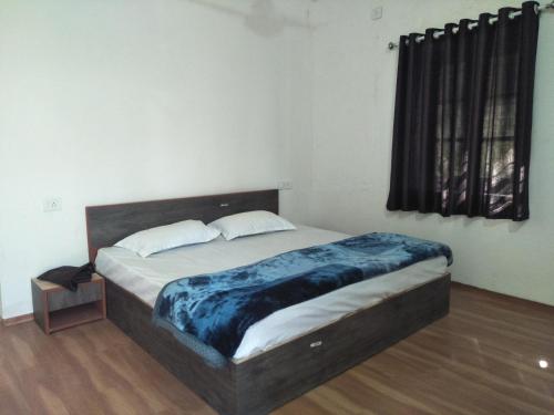 Palms View Villa في مونت ابو: غرفة نوم عليها سرير وبطانية زرقاء