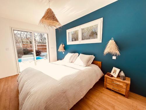 een slaapkamer met een groot bed met een blauwe muur bij Chez Karine & Eric in Le Teich