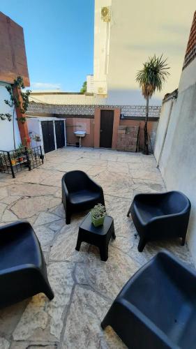 patio z czarnymi krzesłami i stołem oraz budynek w obiekcie Meraki Classic w mieście Villa Carlos Paz