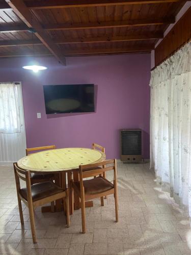 stół i krzesła w pokoju z fioletową ścianą w obiekcie Balcarce 3842 w mieście Olavarría