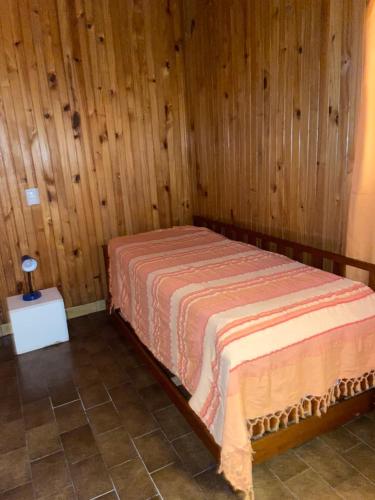 1 dormitorio con 1 cama en una pared de madera en Balcarce 3842 en Olavarría