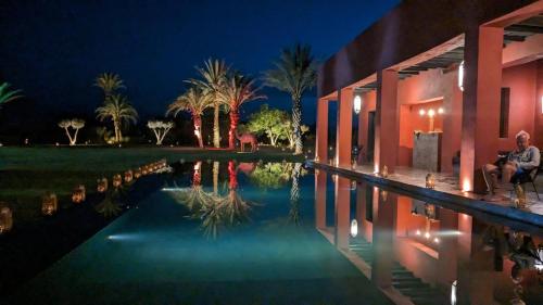 a man sitting next to a swimming pool at night at DAR NOUJOUM in Marrakech