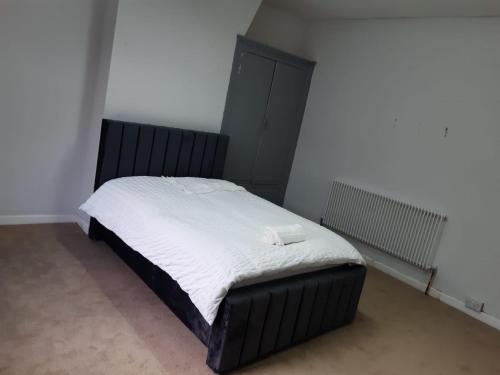 ein Schlafzimmer mit einem großen Bett mit weißer Bettwäsche in der Unterkunft Cozy large double RM 10 in Oldham