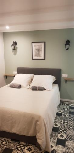 una camera da letto con un grande letto bianco con due cuscini di L'EAU QUI DORT - Chambres et Tables d'hôtes a Pleslin-Trigavou