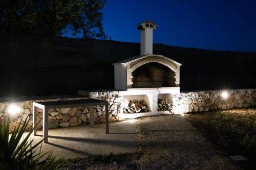 a stone building with a table in front of it at night at Trullo Grazioso Luxury in Ceglie Messapica