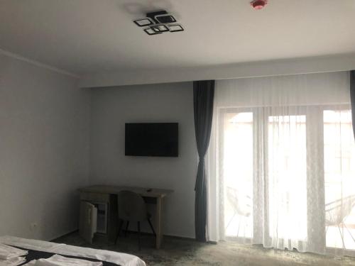 a bedroom with a bed and a desk and a window at Sub Cetate in Râşnov