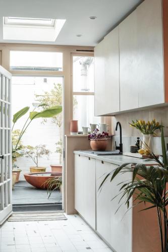 a kitchen with white cabinets and a large window at Boutique Beach Retreat in Westward Ho