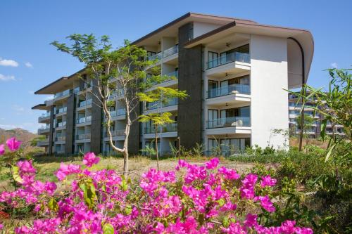 un edificio de apartamentos con flores rosas delante de él en W Costa Rica Resort – Playa Conchal en Playa Conchal