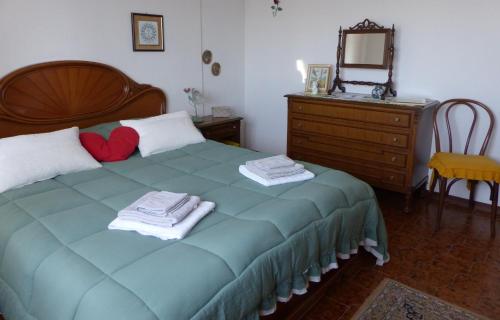 a bedroom with a bed with a heart pillow and a dresser at La casa di Silvia in Massarosa