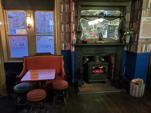 a room with a fireplace and a table and chairs at The Queens Arms Hotel in Acomb