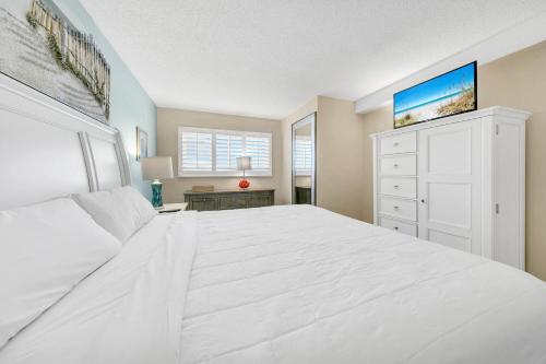 a white bedroom with a large white bed and a dresser at The Summit 1426 in Panama City Beach