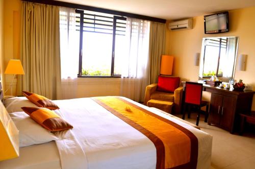 a bedroom with a large bed with a desk and a chair at Nirmala Hotel & Convention Centre in Denpasar