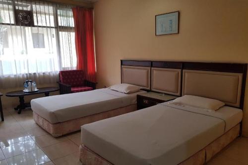 una habitación de hotel con 2 camas y una silla en Siantar Hotel Pematangsiantar, en Pematangsiantar