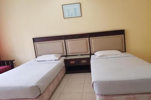 dos camas sentadas una al lado de la otra en una habitación en Siantar Hotel Pematangsiantar, en Pematangsiantar