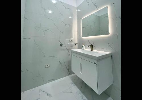 a white bathroom with a sink and a mirror at Hotel Krial in Berat