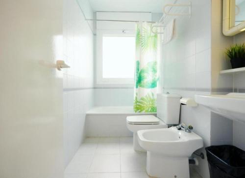 a white bathroom with a toilet and a window at Apartamento Duplex Voramar in S'agaro