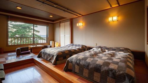 a bedroom with two beds and a desk and a window at Katakurinohana in Senboku