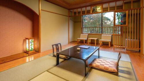 a dining room with a table and chairs and a window at Katakurinohana in Senboku