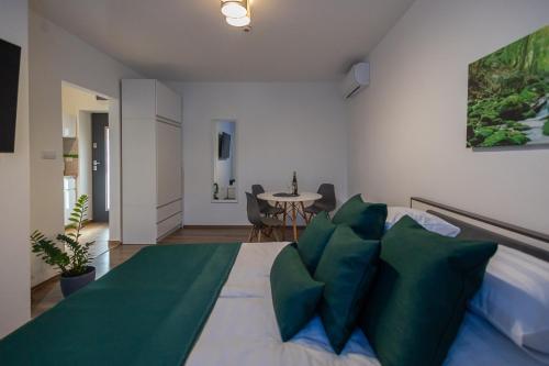 a bedroom with a bed with green pillows and a table at Happy Home Apartman in Miskolctapolca