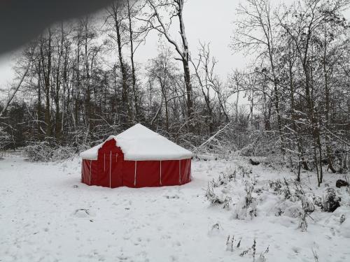 um galpão vermelho coberto de neve num campo em Jurten im Garten Eden BUB em Gützkow