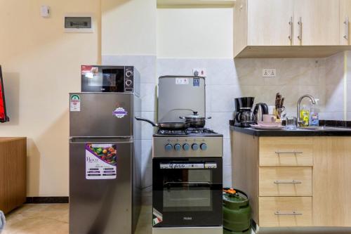 uma pequena cozinha com um fogão e um frigorífico em Iconic Stays em Eldoret