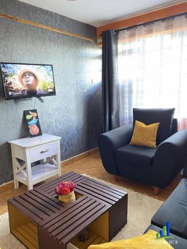 uma sala de estar com um sofá azul e uma mesa em Iconic Stays em Eldoret