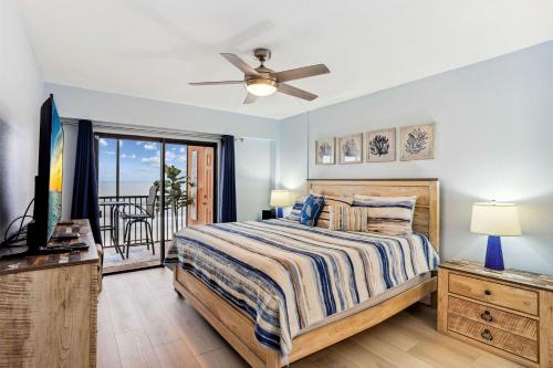 a bedroom with a bed and a television and a balcony at Villa Madeira 408 - Premier in St Pete Beach