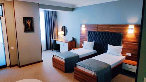 um quarto de hotel com duas camas e uma secretária em Royal Boutique Baku em Baku