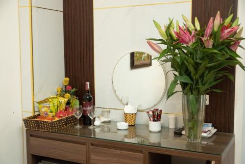 einen Tisch mit einer Vase aus Blumen und einem Spiegel in der Unterkunft Hà Thành Hotel - Ngõ 63 Lê Đức Thọ, Mỹ Đình - by Bay Luxury in Hanoi