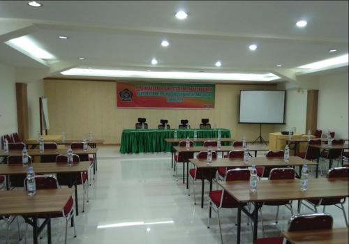 una clase con mesas, sillas y una pantalla en Siantar Hotel Pematangsiantar, en Pematangsiantar