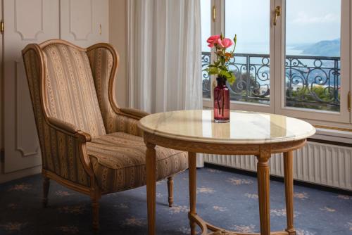 a table and a chair with a vase of flowers at Hotel Victoria Glion in Montreux