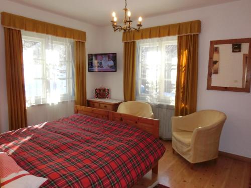 a bedroom with a bed and a desk and windows at OLIMPIA LODGE in Cortina dʼAmpezzo