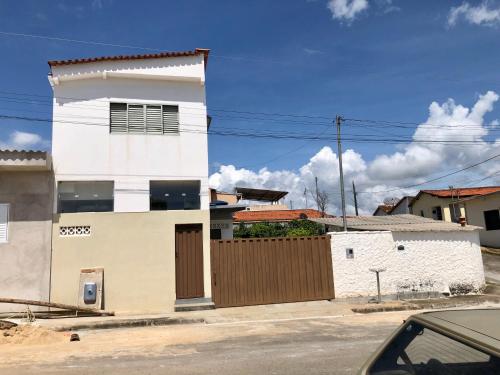 ein weißes Gebäude auf einer Straße mit einem Zaun in der Unterkunft Serra da Canastra - Casa em Vargem Bonita/MG in Vargem Bonita