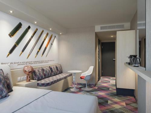 una camera d'albergo con letto, divano e tavolo di Science Hotel Prémium a Szeged