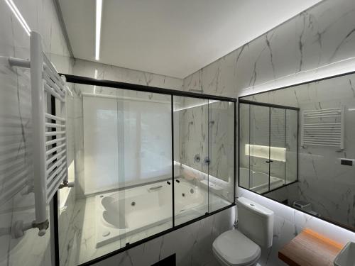 a bathroom with a glass shower and a toilet at Pousada Encontro das Águas in Gonçalves