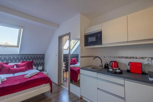 1 dormitorio con cama roja y cocina en Happy Home Apartman, en Miskolctapolca