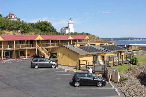 a building with cars parked in a parking lot with a lighthouse at Port Townsend Inn in Port Townsend