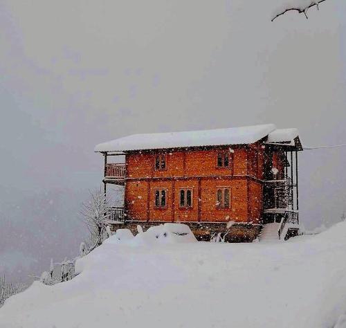 ein Backsteingebäude im Schnee mit Schnee darauf in der Unterkunft Wooden House Garetke in Batumi