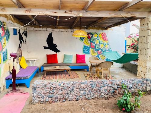 a patio with colorful furniture and a bird painted on the wall at Blue House in Lighthouse in Dahab