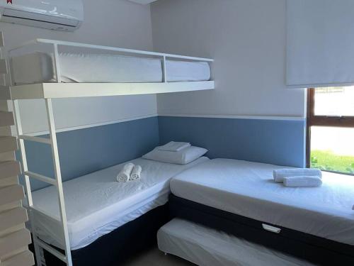 two bunk beds in a room with a window at Apto Luxo - Praia dos Carneiros in Praia dos Carneiros