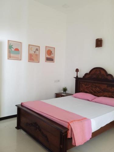 a bedroom with a wooden bed with pink sheets at Villa Ocean Breeze in Ahangama