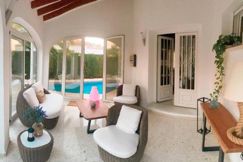 a living room with chairs and a table and a pool at Impresionante Villa con piscina climatizada - OLIVA NOVA in Oliva