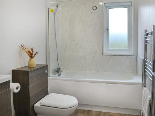 a bathroom with a white tub and a toilet and a window at Harwood Lodge in Wilberfoss